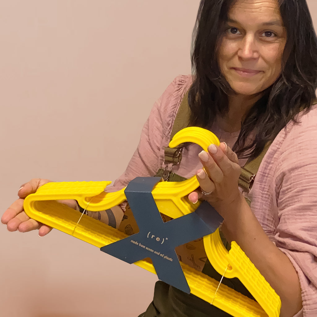Paulina Quintana holds a pack of bright yellow recycled plastic hangers