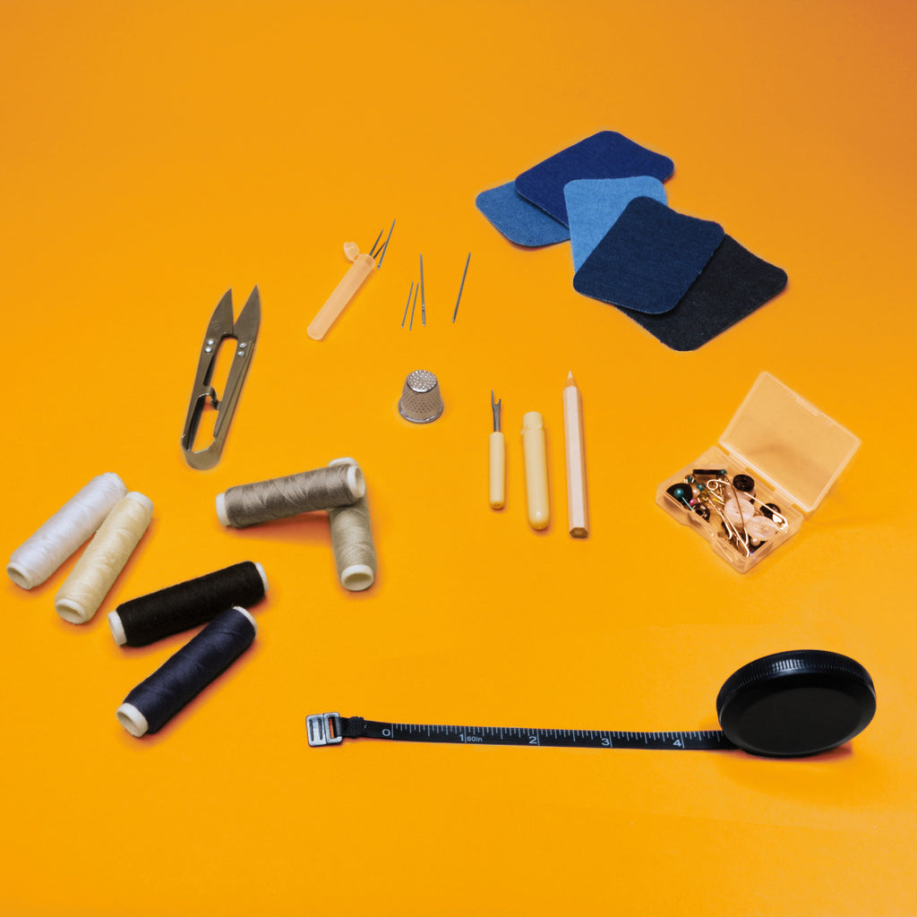 Components of a sewing kit laid out on an orange surface