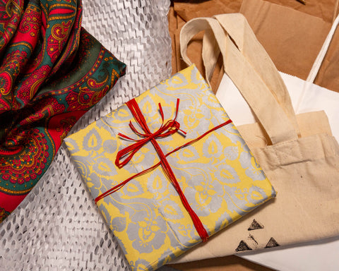 A mix of alternatives to wrapping paper: brown craft paper, recycled papers, raffia ribbon, paper and cloth bags, and a wrapping cloth