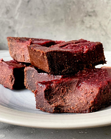 brownies with a distinctive red hue stacked on a light colored plate