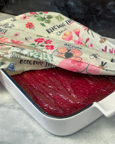 A white ceramic baking dish with red-hued brownies covered in a Bees Love These Z Wrap