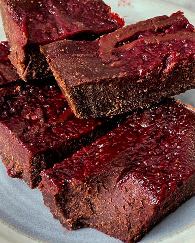 Fudgy red-fruit topped brownies on a light plate