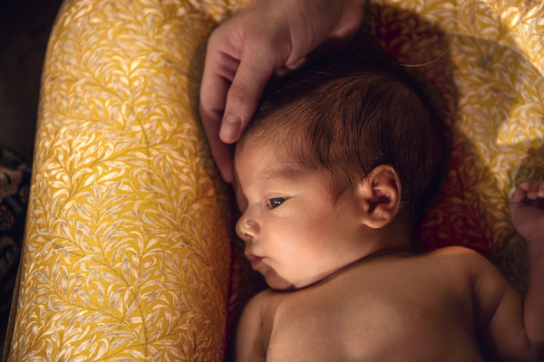 Baby lying in a DockATot Deluxe+ dock in Golden Willow Boughs