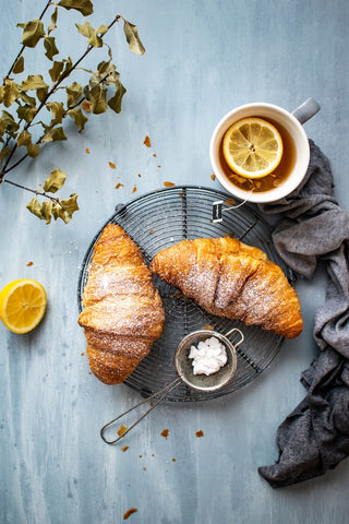 Plate of croissants and lemon tea set out on a table