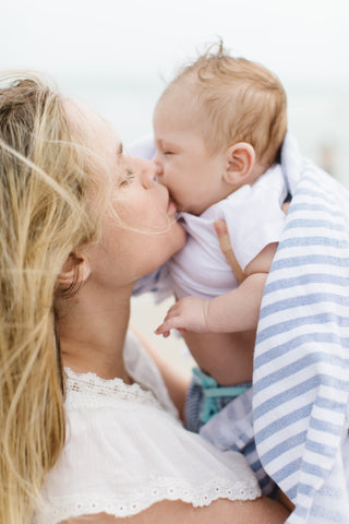 Mother kissing baby on the beach