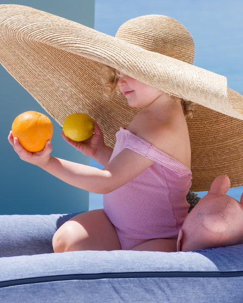 Child sitting in a DockATot Indigo Chambray dock