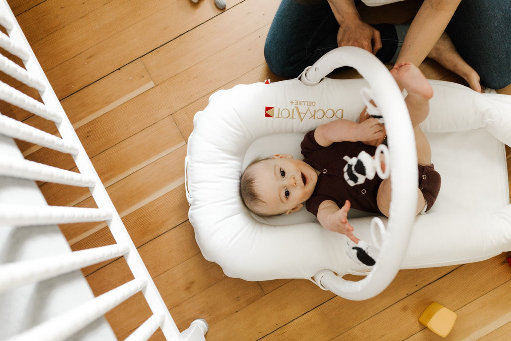 baby plays with dockatot toy arch