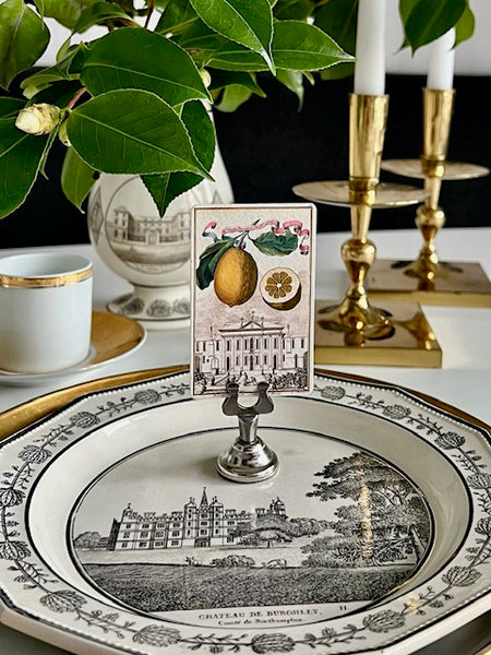 The Punctilious Mr. P's Place Cards Co. "Citrus Garden" place card on "simple holder" in silver on gray faience china with brass candlesticks