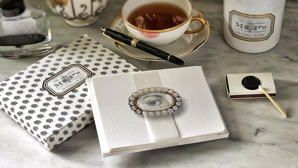 The punctilious Mr. P's lover's eye note cards on a table with a cup of tea, montblanc pen and mr. p's twilight candle