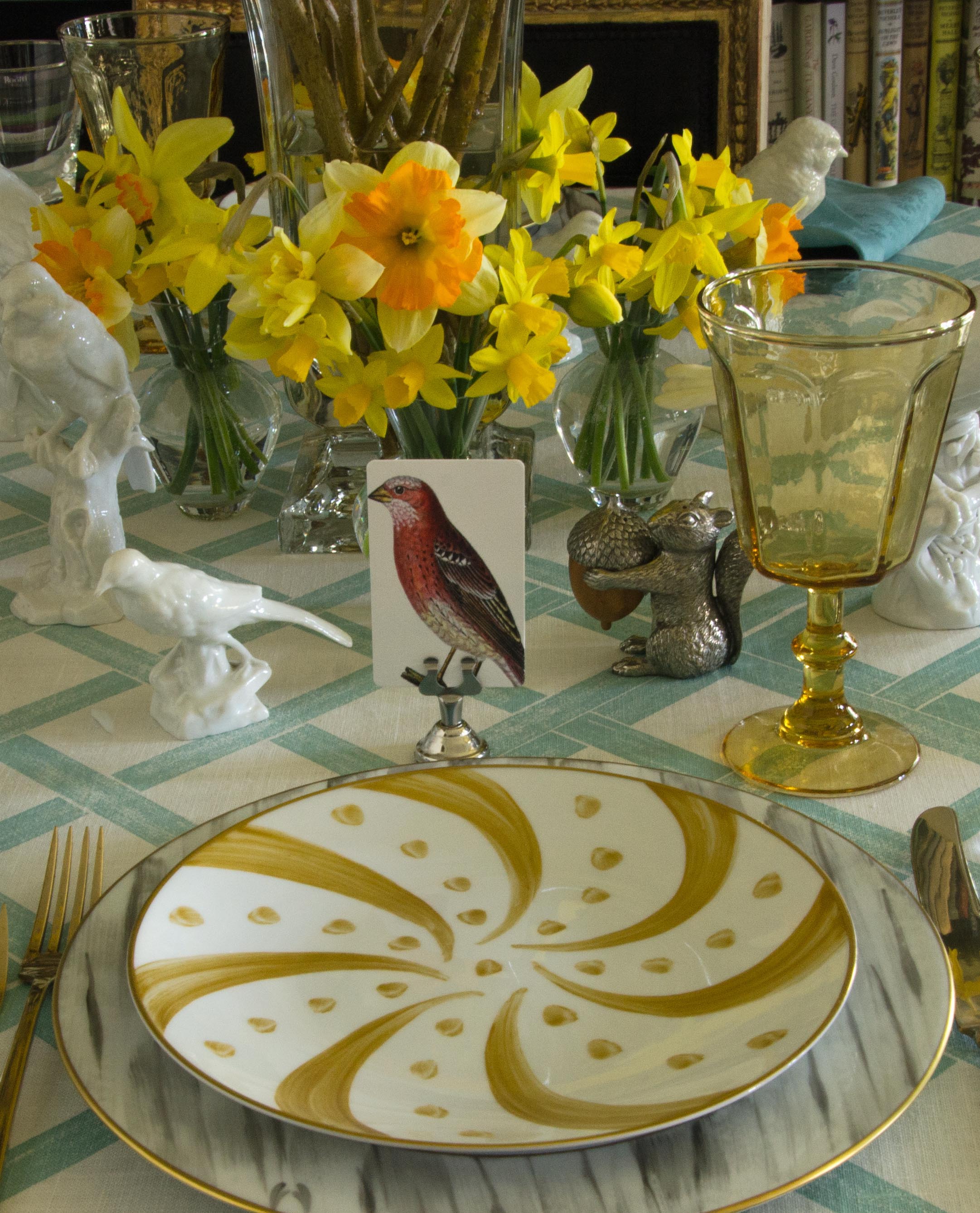 The Punctilious Mr. P's Place Cards Co. "Chromatic Cuckoo" Red Bird custom place card on "simple holder" in silver on China Pattern with Hand Painted Gold Border with Daffodil flower arrangement