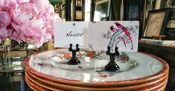 The Punctilious mr. P's place card co. showing a beautiful birds place cards on top of a stack of china plates and peony in the background