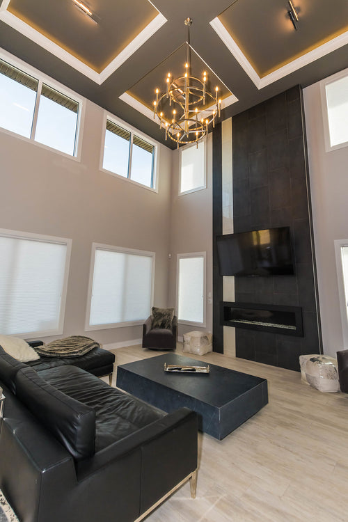 Light grey floor tile, black and white floor to ceiling fireplace tile, linear fireplace, black sectional couch, grey side chairs. 