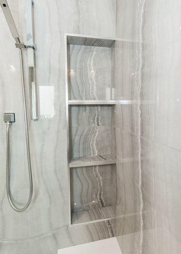 Grey travertine tiles, white quartz bench top, white freestanding tub, and chrome plumbing fixtures.