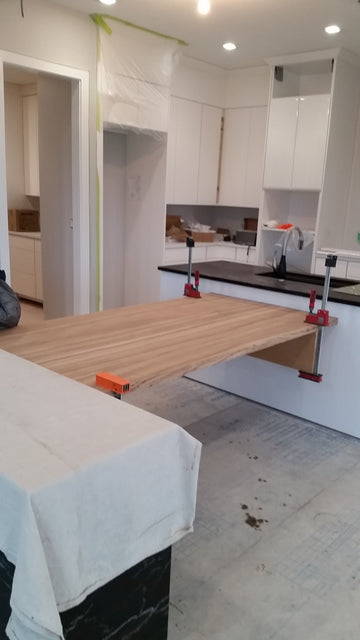 Black granite island, light grey wood tile, floating wood dining room table.