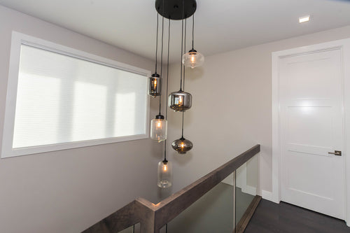 Dark grey hardwood, pendant glass fixtures, grey stairwell with clear glass railing.