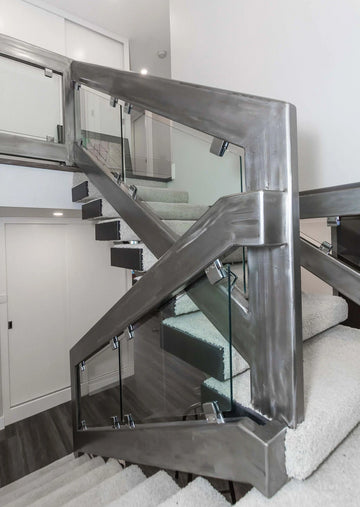 Light grey walls, sanded steel railing with clear glass inserts. Carpet stairs.