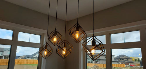 Linear dining room light with 5 black cubed geometric pendants.