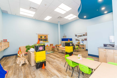 Light vinyl flooring, blue wall details, dark blue curved bulkhead, and light maple furniture with green chairs.