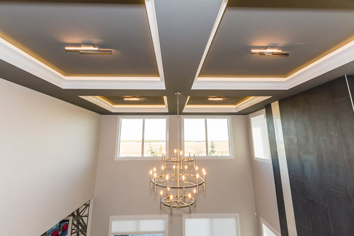 Grey coffered ceiling, white trim details, dark grey tile on right wall, and a large satin nickel chandelier.