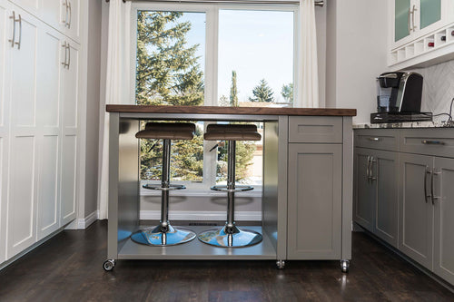 Grey island with open space for stools. Brown and grey vinyl floor, white pantry cabinets on the left and grey lower cabinets on the right.