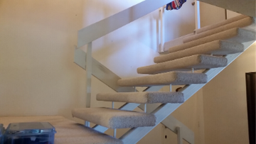 Before staircase. Beige carpet, beige metal railing.