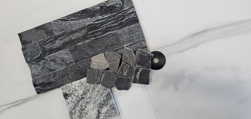 Bathroom selection samples. Marble looking porcelain tile, black and grey stacked stone, grey pebbles, white cabinets, and black and white granite.