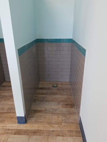 Blue wall toilet space. Grey and teal subway tile.