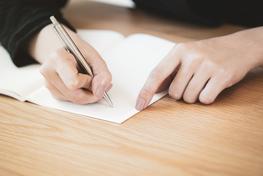 Lady signing paper on light countertop.