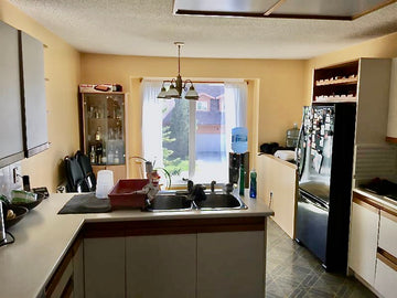 White melamine cabinet doors with recessed oak cabinet pulls. Green lino, yellow walls and a small sunshine ceiling.