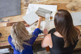 Two ladies touching samples on table.