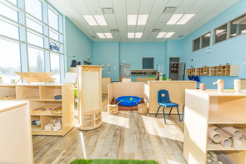 Light vinyl flooring, large windows, blue wall details, and light maple furniture with green chairs.