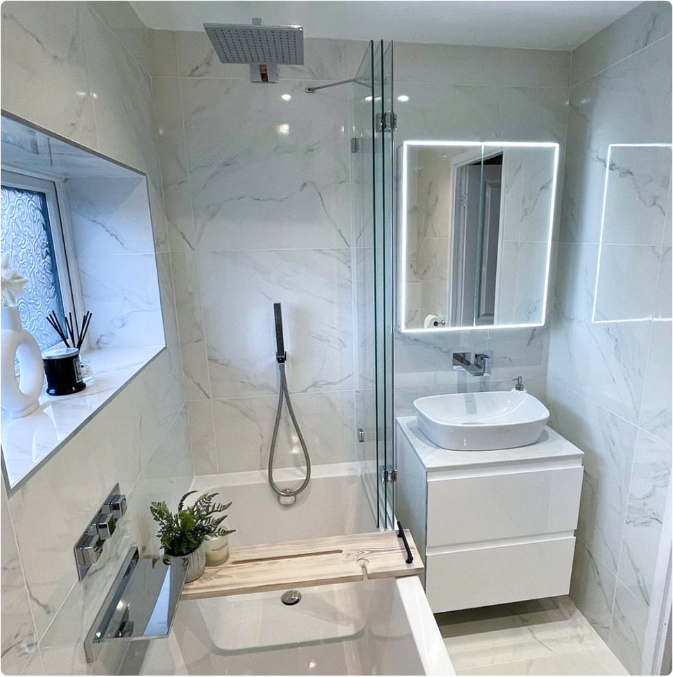 Image of a small bathroom renovation. Including a shower bath, over bath shower, vanity unit and mirror. Toilet is at the other end, but not shown in the image.