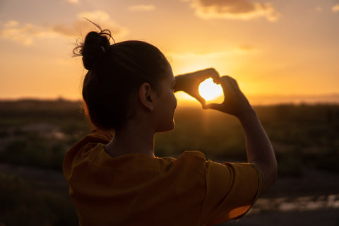 Lady Making Heart Sign Over Sunset