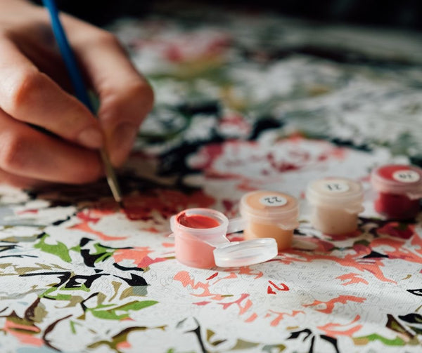 A person paints a paint-by-numbers floral project