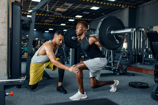 Athlete working out at a gym while being coached by his trainer on the best time to drink a protein shake