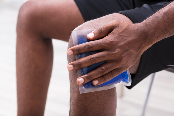 Man applying ice gel pack on his knee to prevent knee pain when running