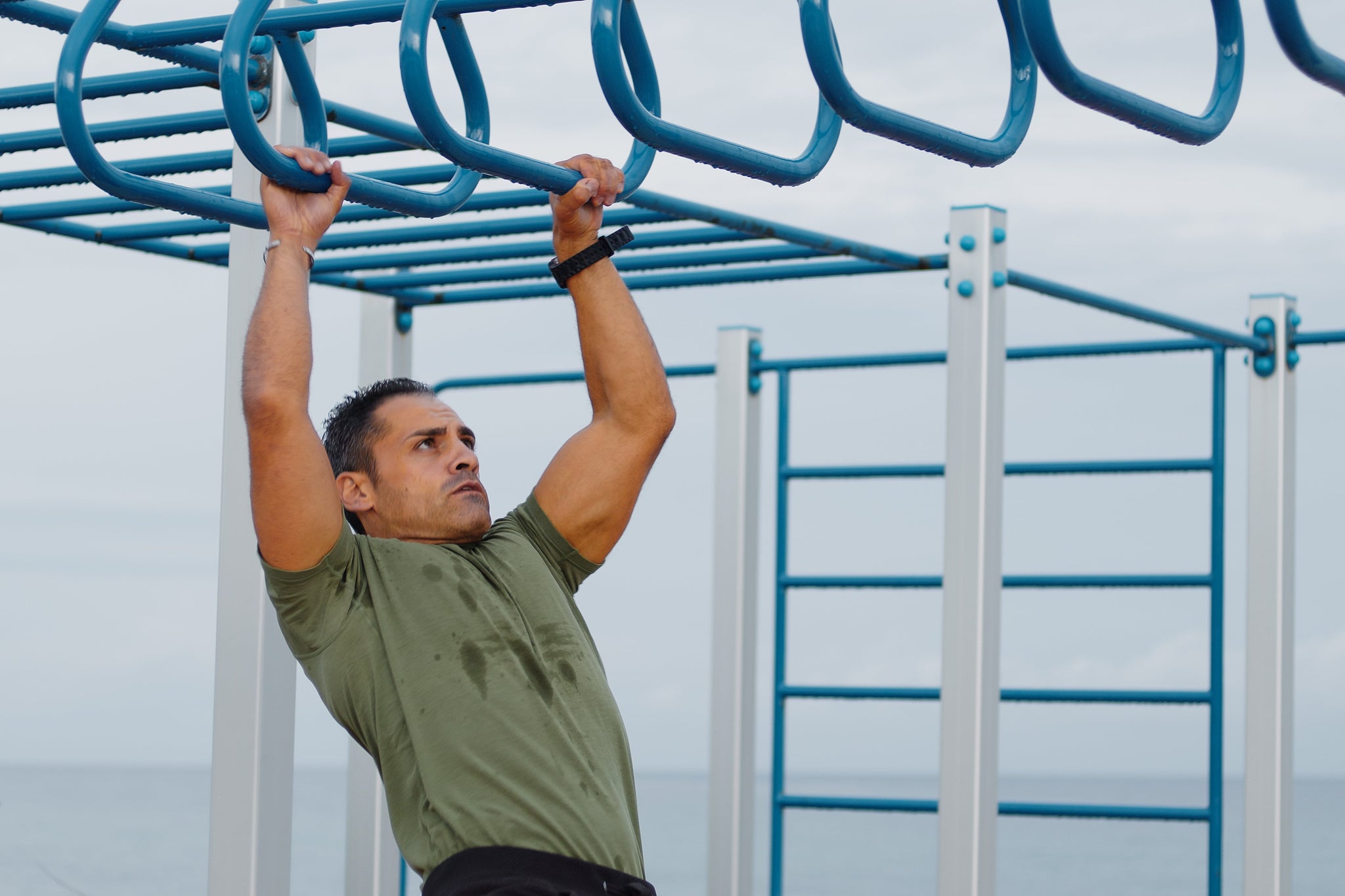 Man doing pull ups across monkey bars as part of his intermittent fasting workout