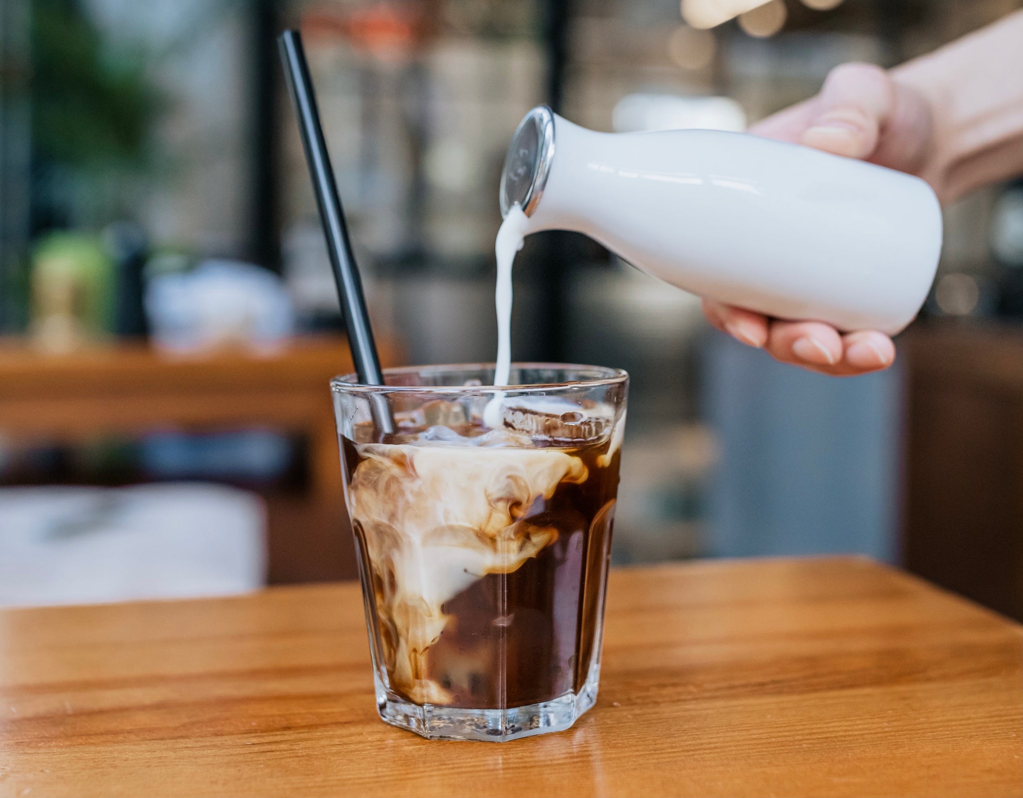 Athlete pouring liquid collagen into a glass of coffee to make caffeine protein shake