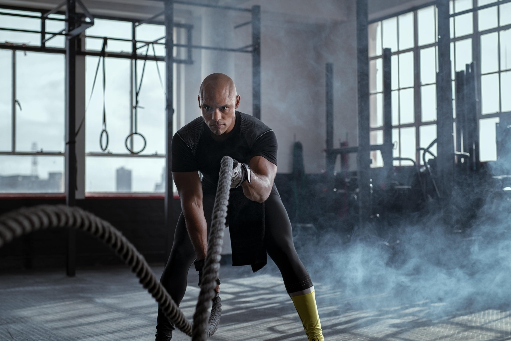 Athletic man doing crossfit battle rope exercise at a gym is wondering about how to make collagen a complete protein