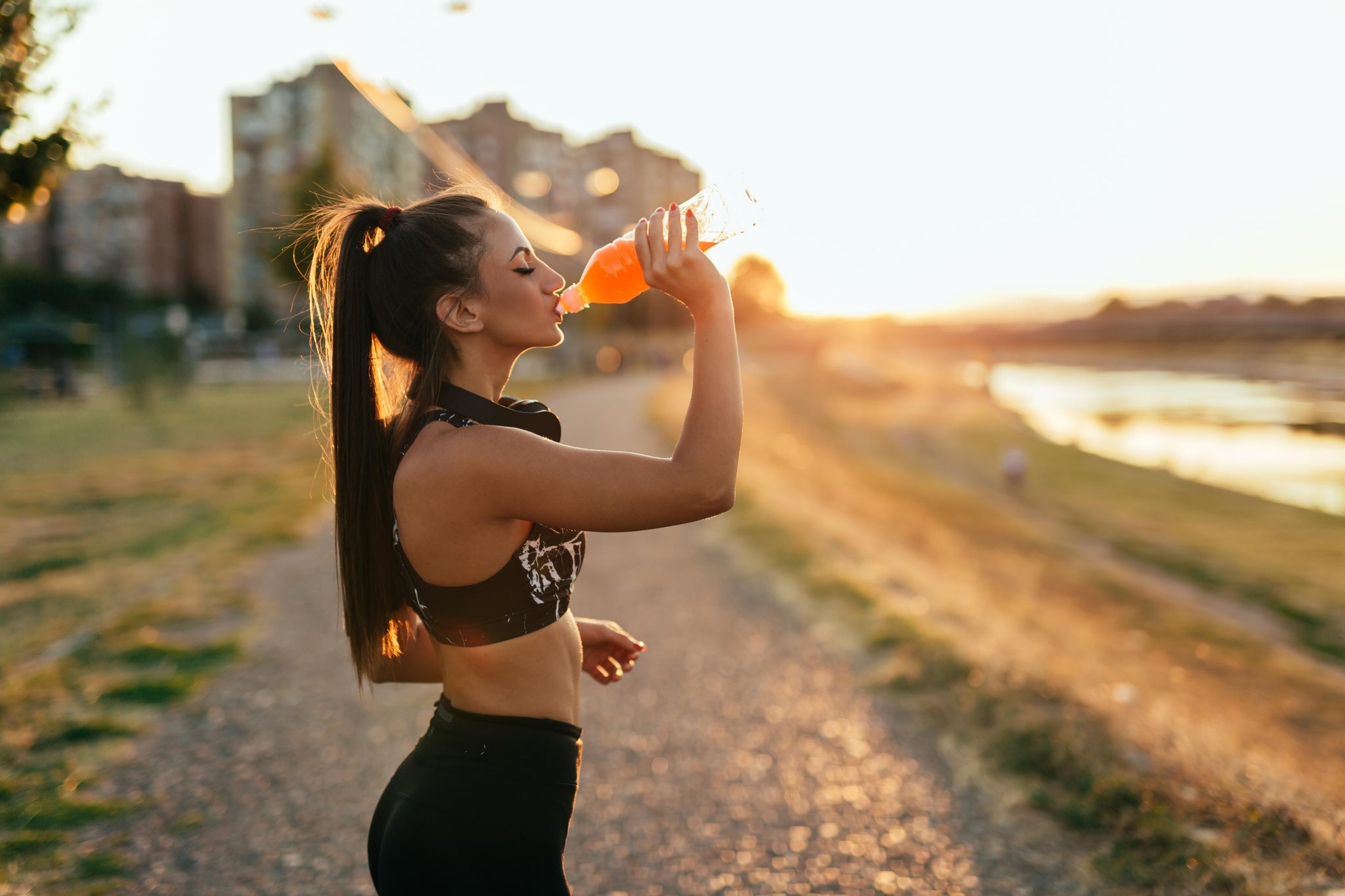 Fit woman in athletic wear is drinking a bottle of a sports nutrition product