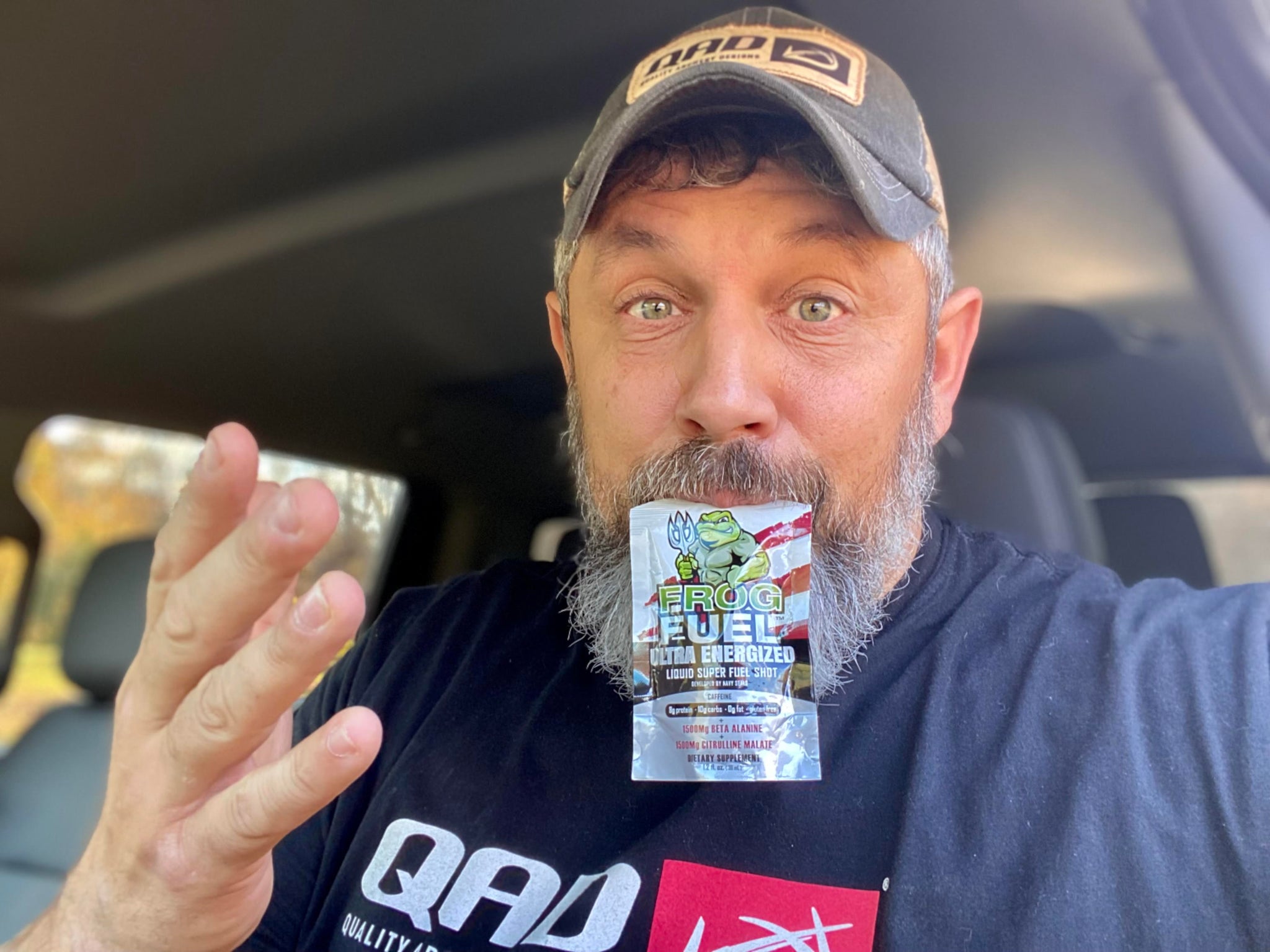 Hunter with full beard and a cap is holding a packet of Frog Fuel liquid collagen, an easy-to-digest deer hunting snack, in his mouth