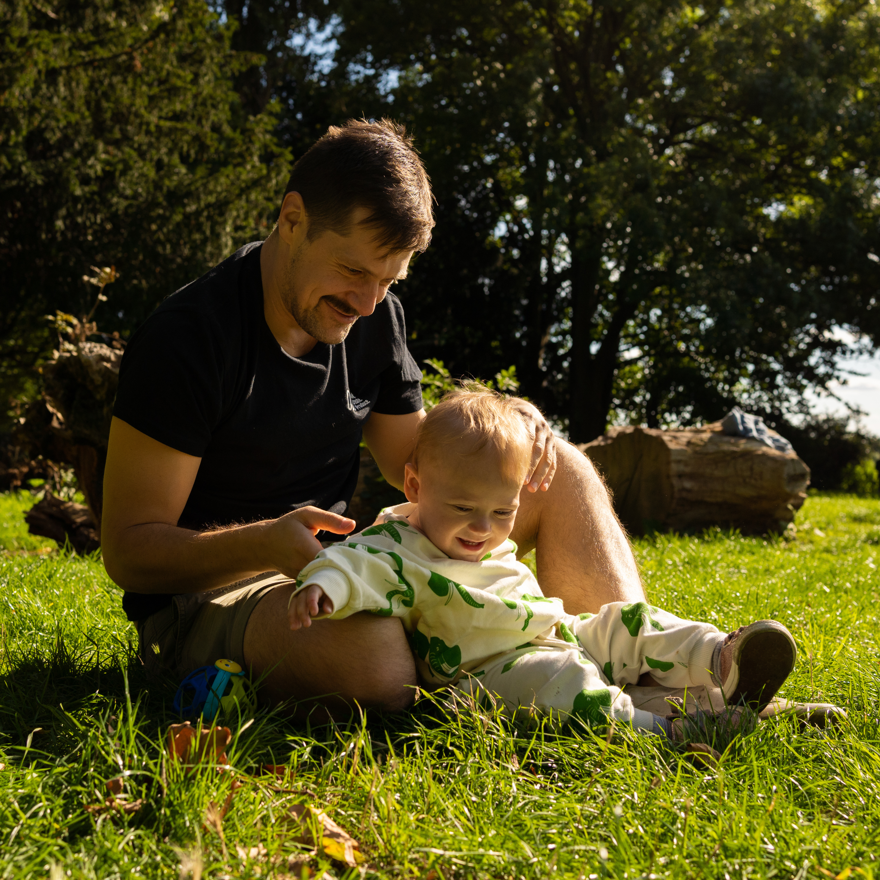 Baby sat in the grass with dad in rented baby clothes - rent baby clothes