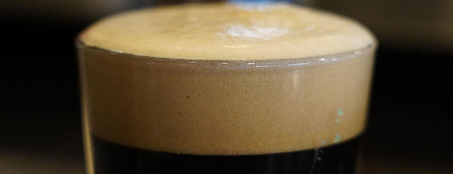 Close-up photo of pint glass filled with stout beer poured on nitro.