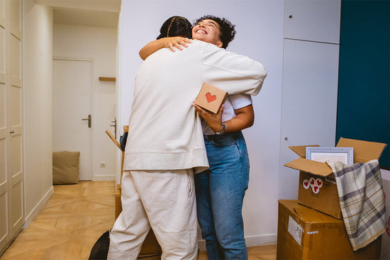 A woman hugging her boyfriend while holding a Lovebox.