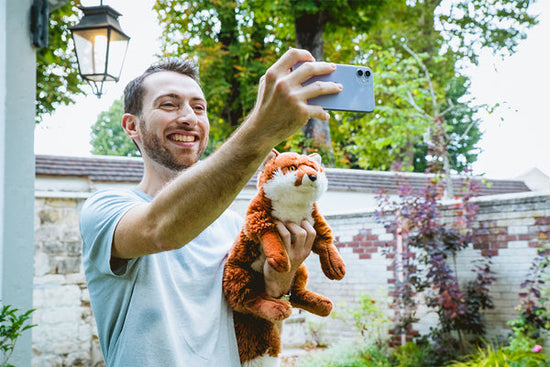 Man taking a selfie with a tiger plush toy.