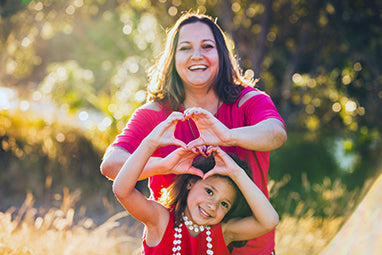 woman in field with daughter both making hearts with hands - omega 3 and heart health