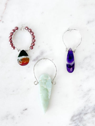 three true happiness designs necklaces. one with an upside down amazonite dagger, one with an amethyst long teardrop and one w/ an agate teardrop hanging down w/ small copper beads wire wrapped around a silver pendant