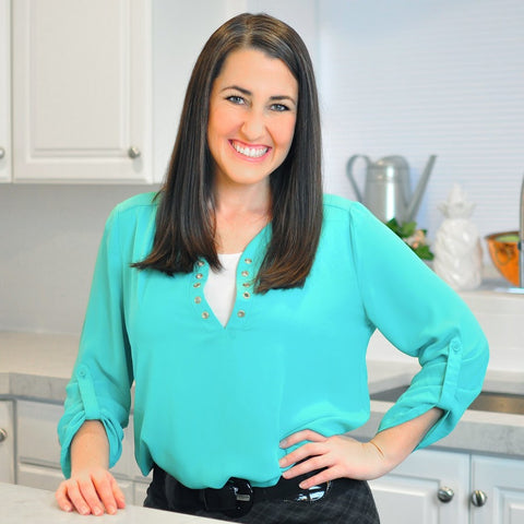 Image of Rachel Farnsworth in a turquoise blouse, smiling and standing in a bright kitchen.