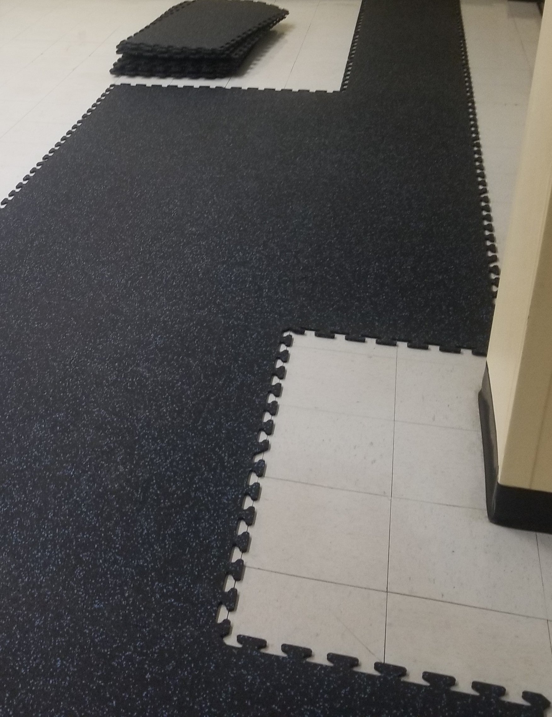 Interlocking rubber tiles being installed over linoleum flooring.