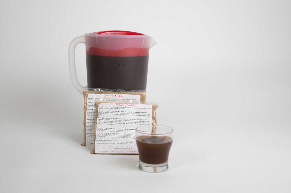 pitcher of essiac tea with two packets and a cup of tea